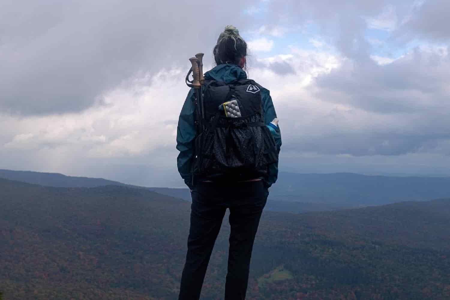 backpacker overlooking a rolling valley with clouds overhead.