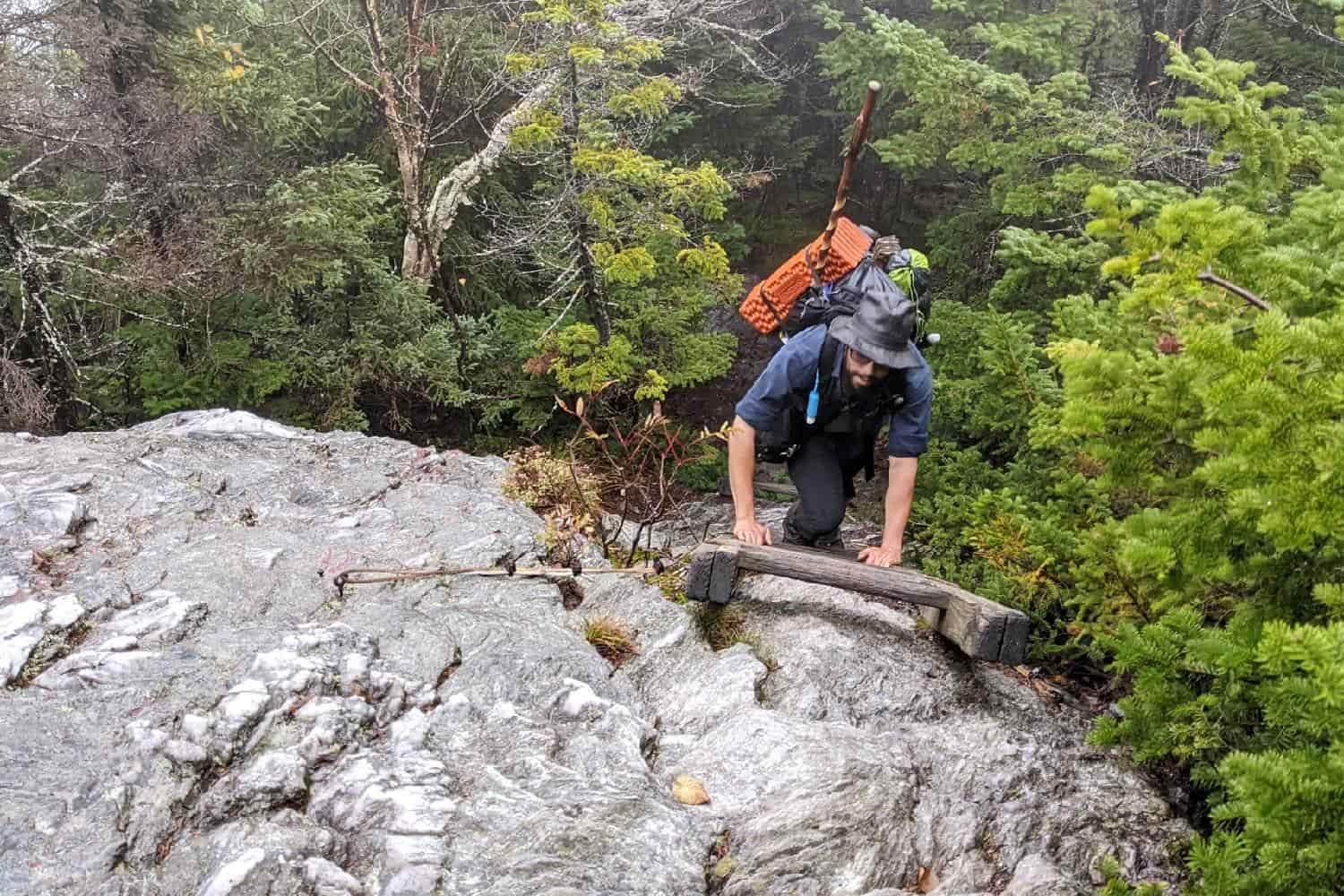 backpacker on the long trail climbing a ladder to get over a steep rock.