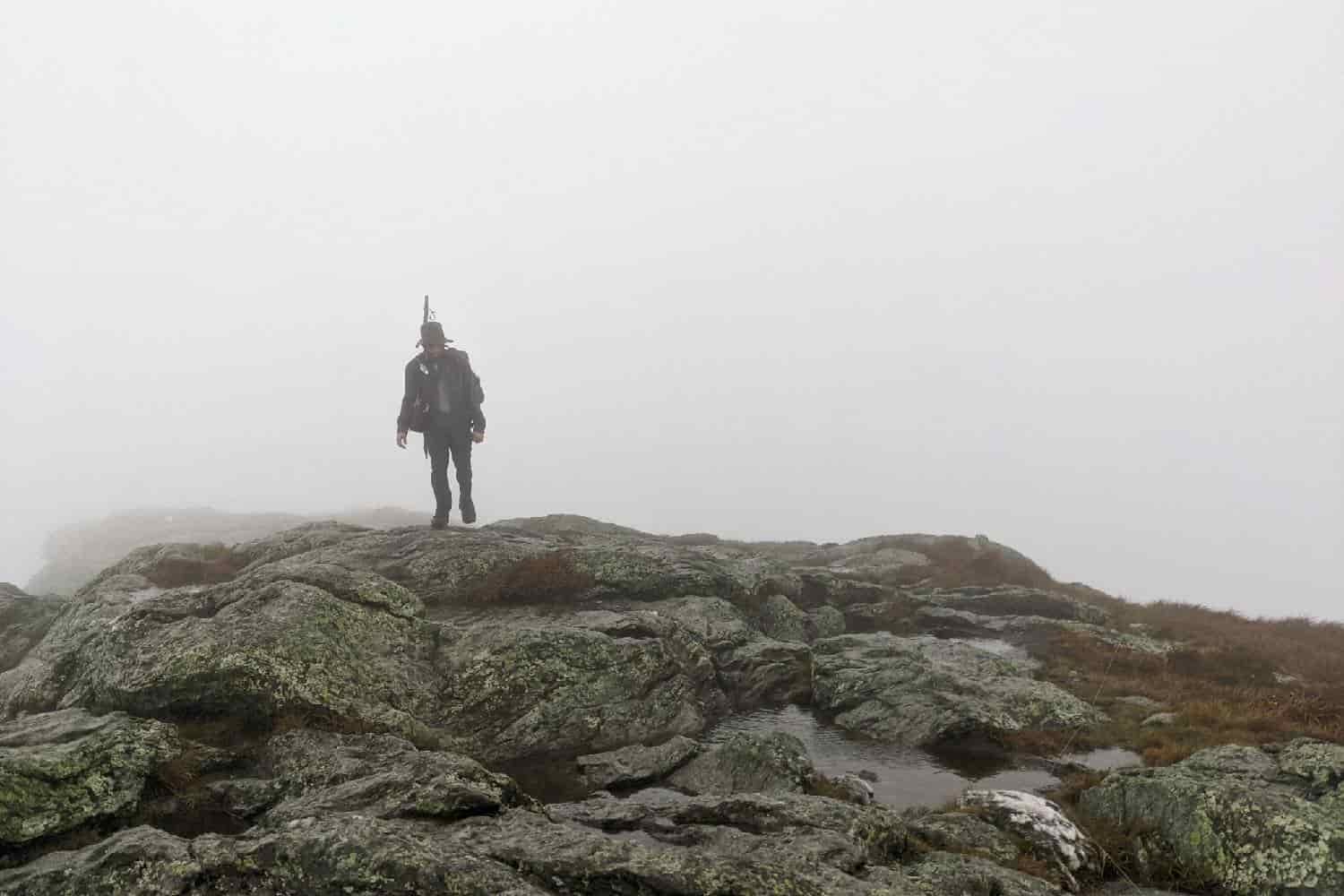backpacker walking on a mountain in the mist.