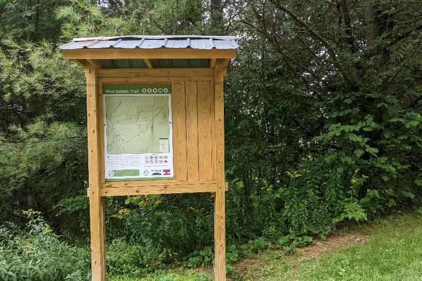 kiosk at a trailhead with a map showing access to pine cobble trail.