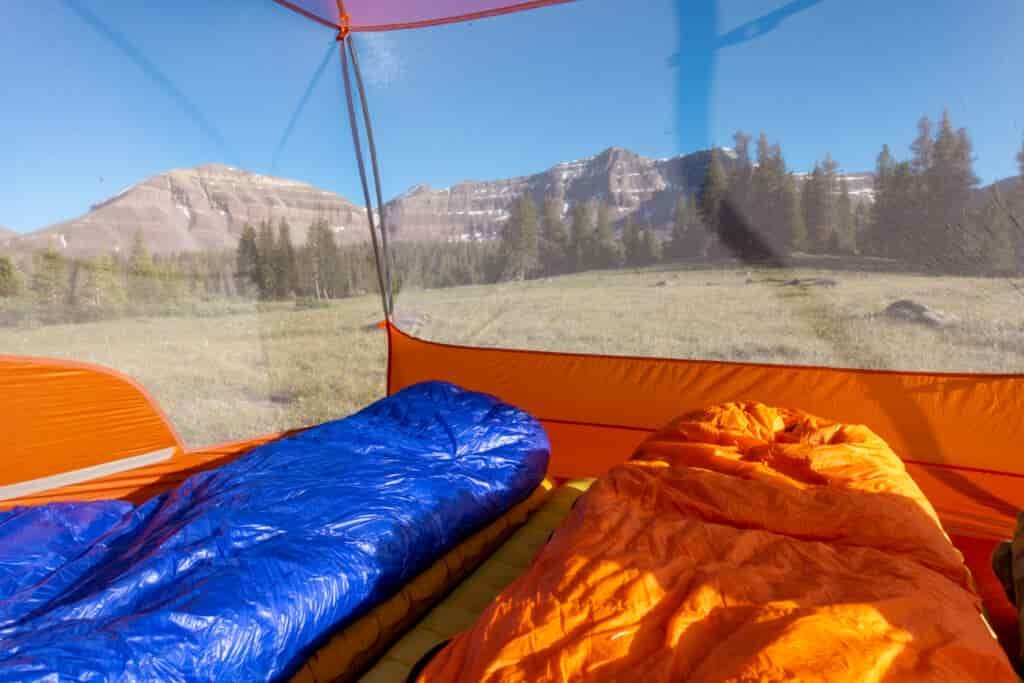 blue and orange sleeping bags inside the mesh walls of a tent