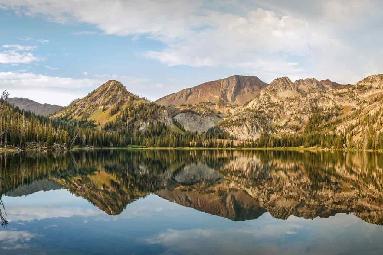 wallowa mountains in the eagle cap wilderness in a golden yellow alpenglow over a still lake reflecting the ridgeline.