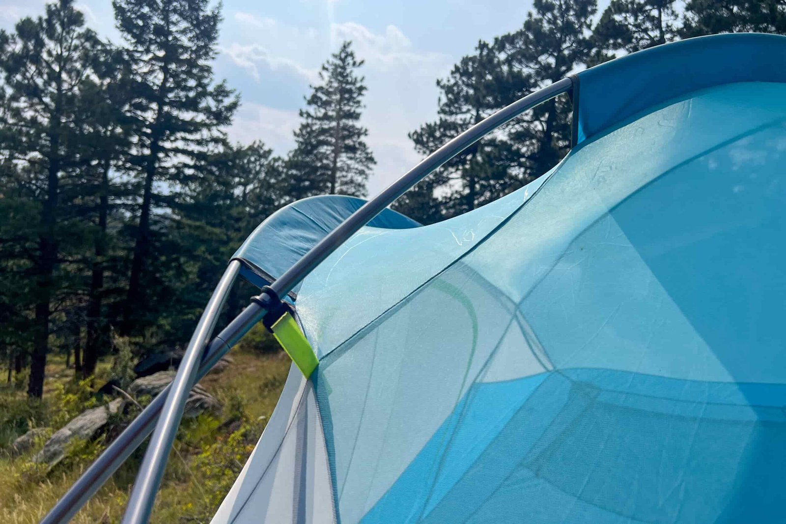 The image shows two tent poles crossing over each other on the left with the mesh tent upper on the right.