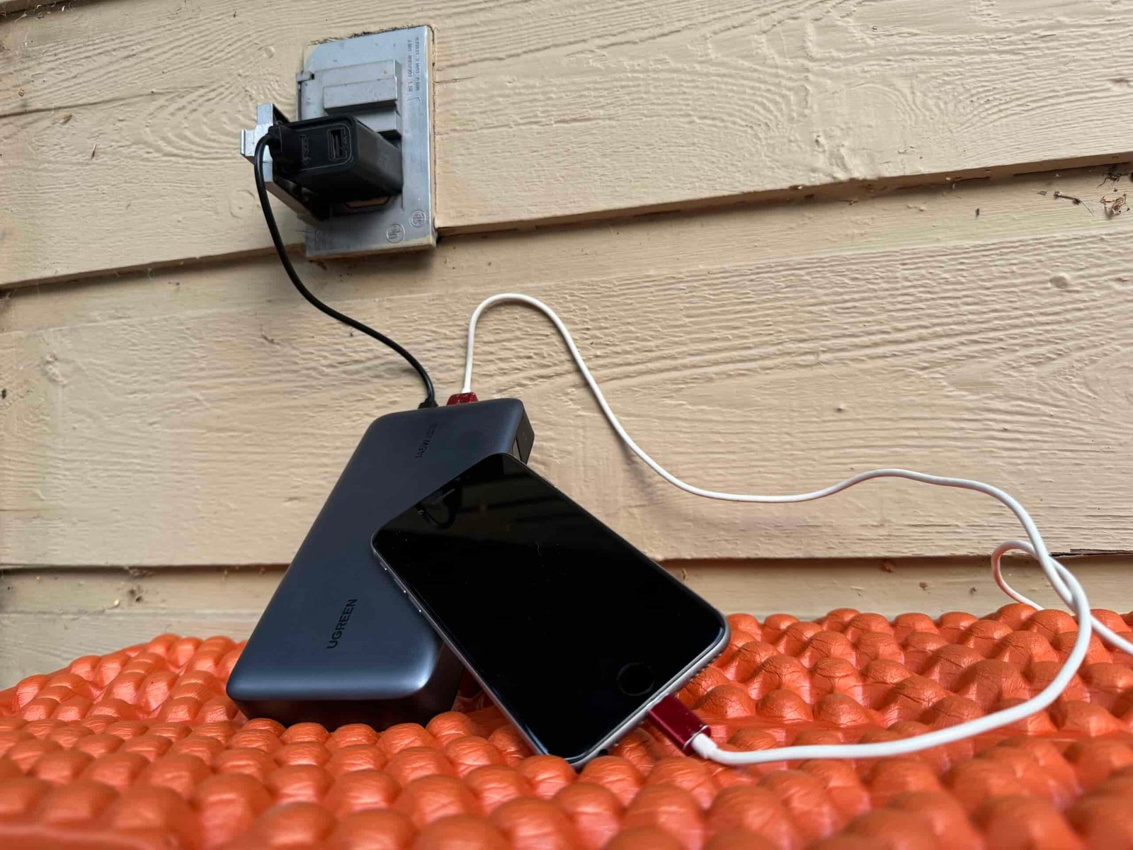 Close up of the UGREEN charging from an outlet and a cell phone charging from the power bank simultaneously.