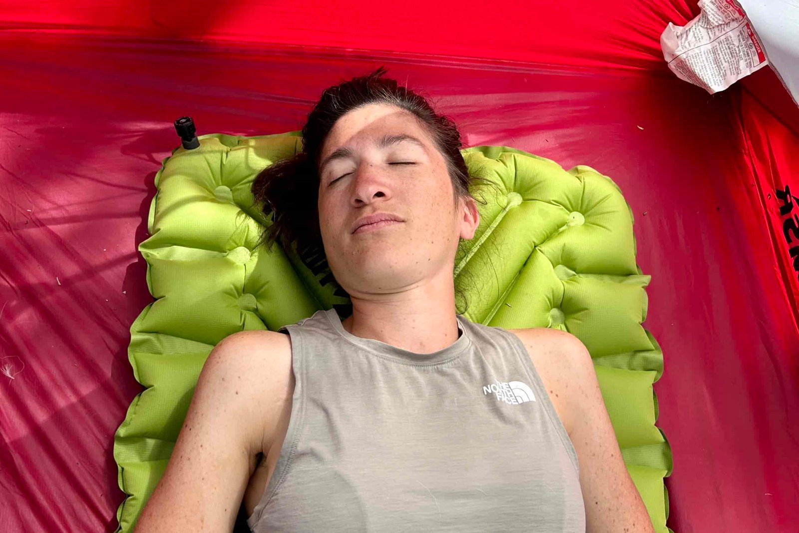 A woman rests comfortably on an air pad in a tent.
