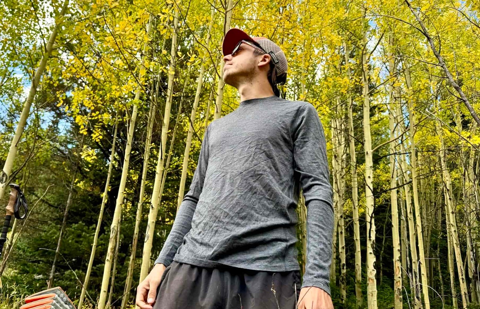 A hiker stands in the woods wearing the Smartwool Classic All-Season base layer. Trees are in the background.