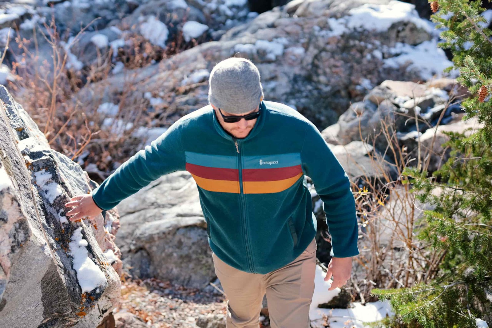 A man walks past a boulder.