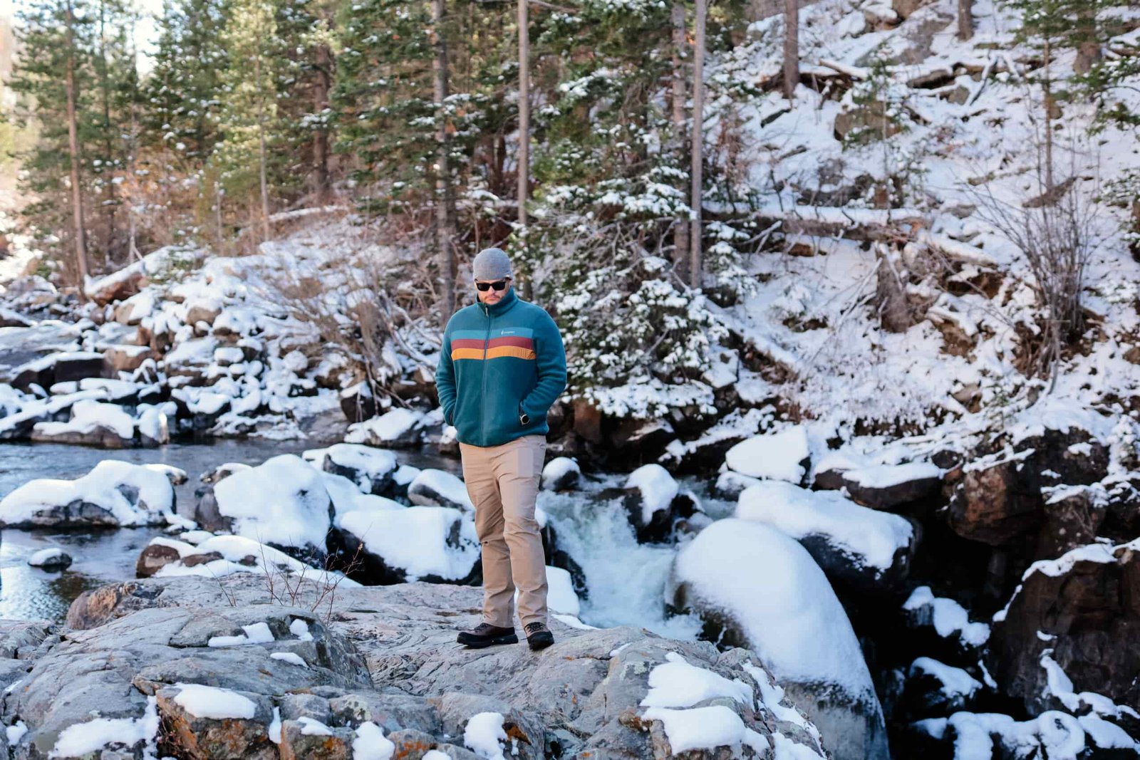 A man stands by a waterfall in the snow.