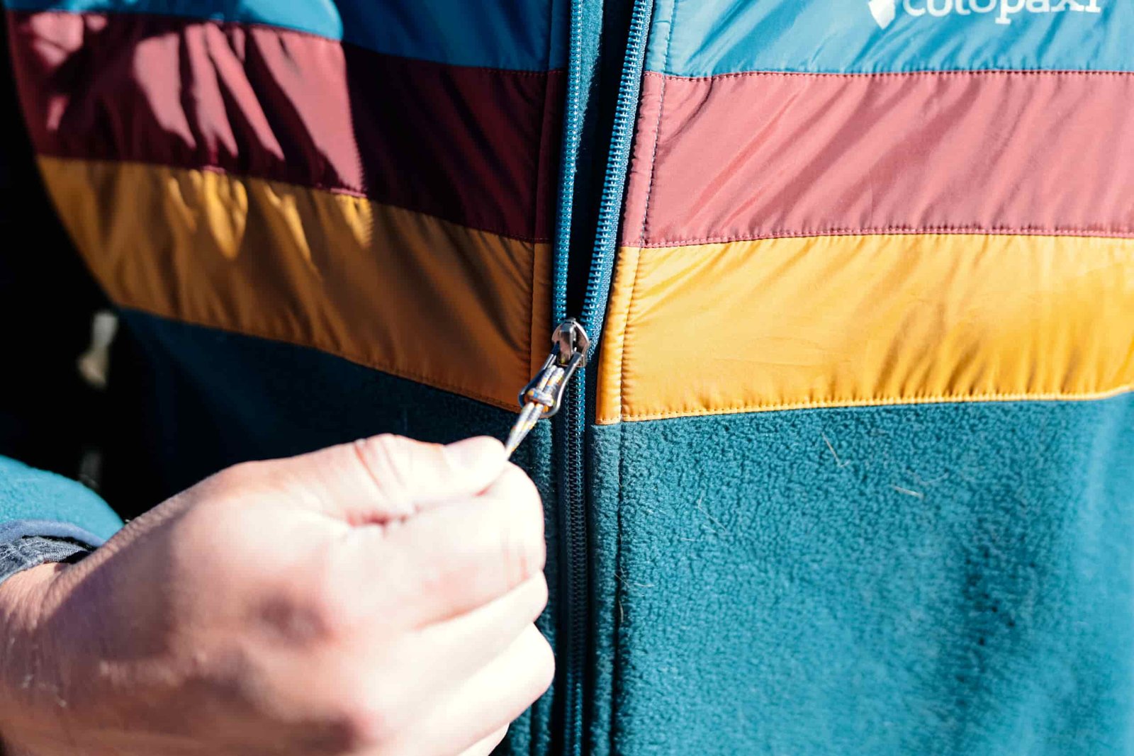A hand zips a jacket.