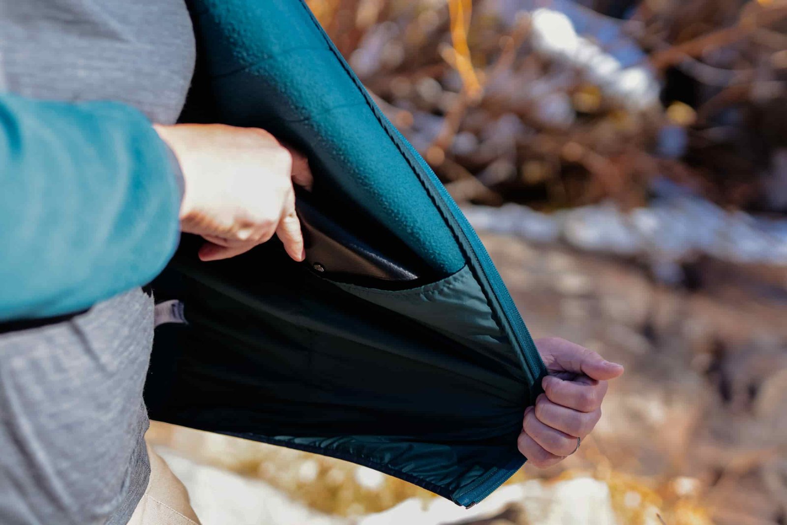A hand pulls a phone from an inside pocket of a fleece jacket.
