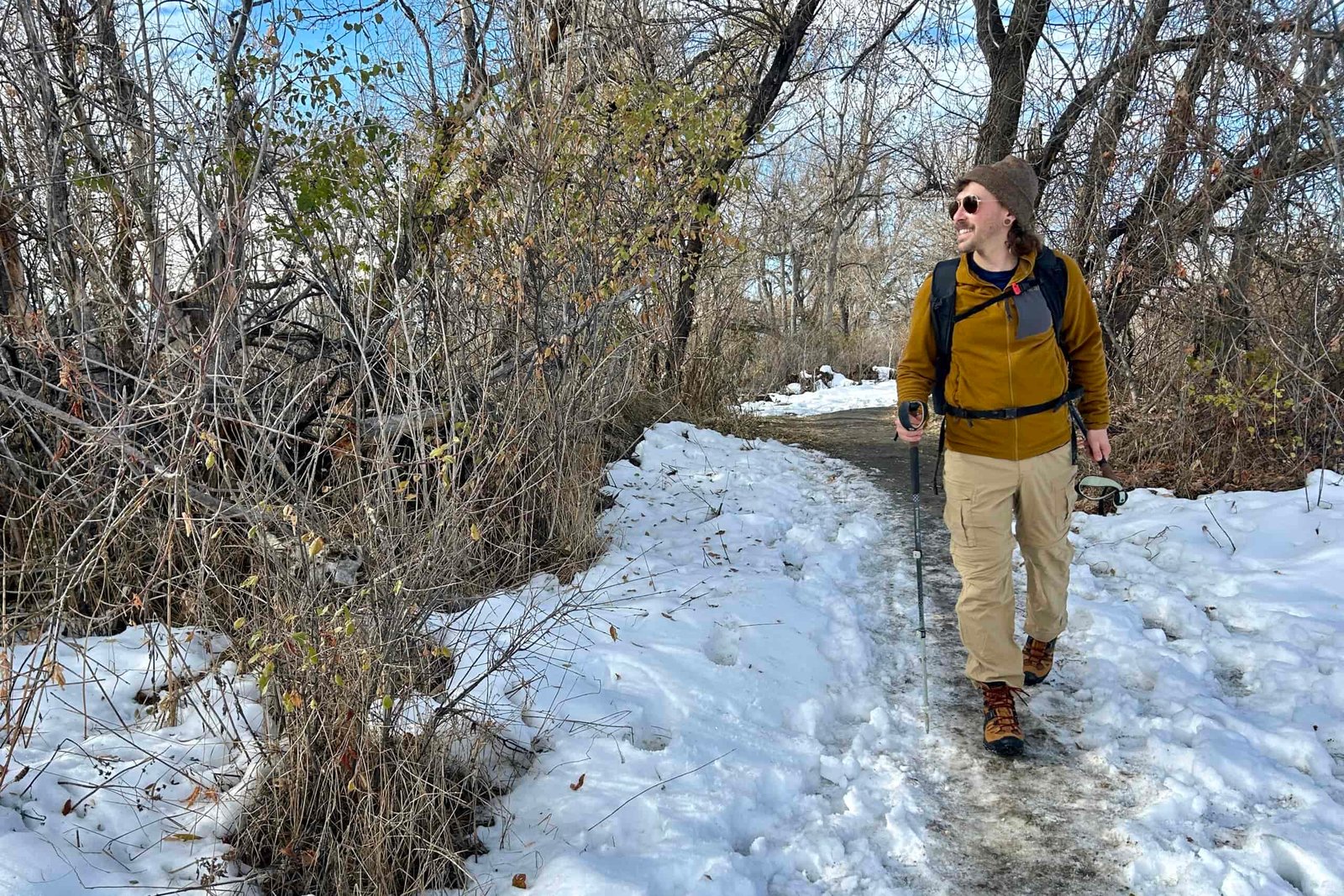 A man hikes through a snowy wilderness area on a bluebird day.