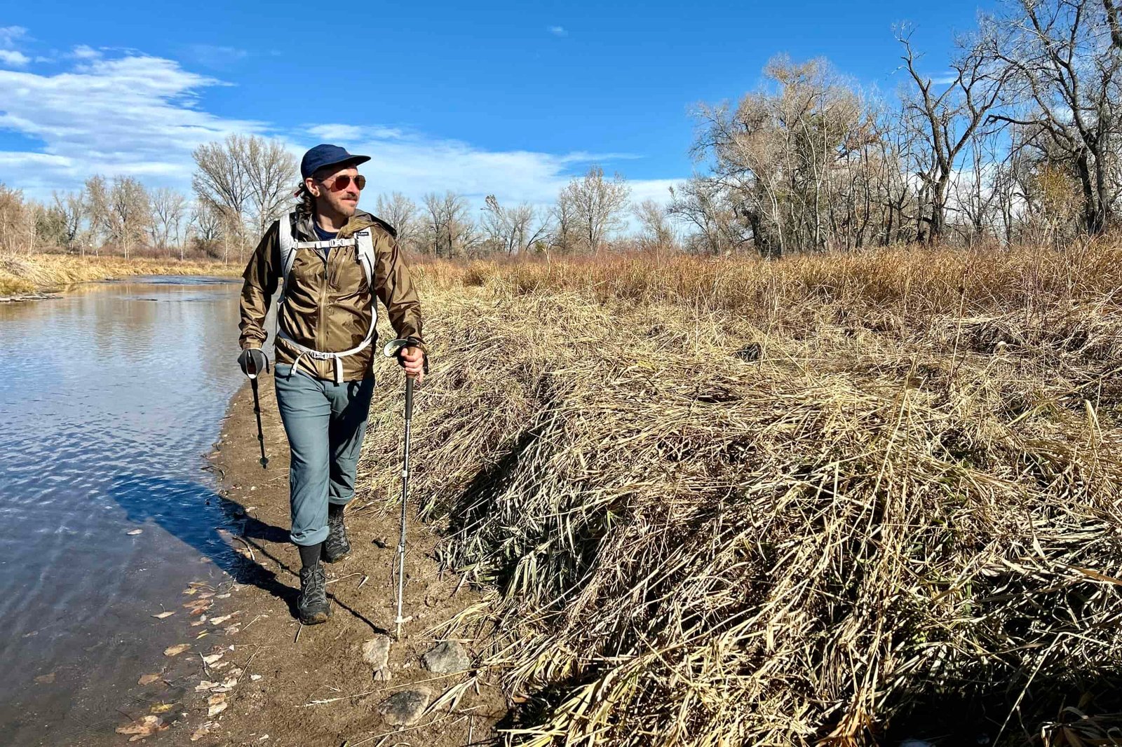 A man hikes along a river in a wilderness area in fall.