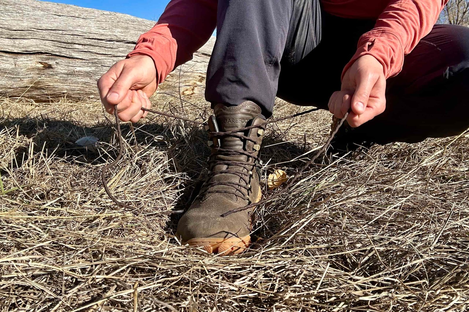Close up image from knees down of a person tying a pair of boots.