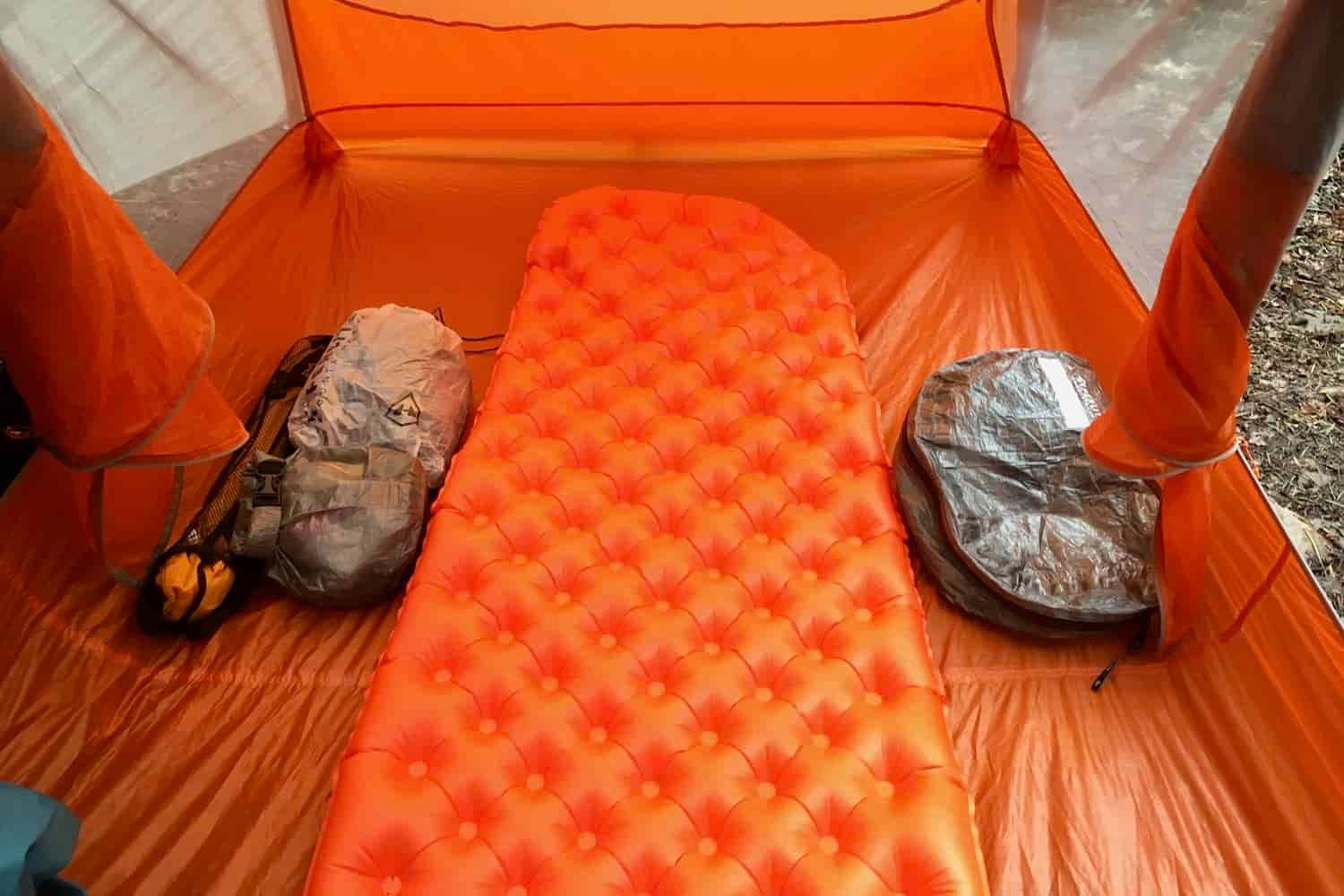a sea to summit ultralight insulated sleeping pad inflated in a backpacking tent with an ultralight pack and pod beside it.