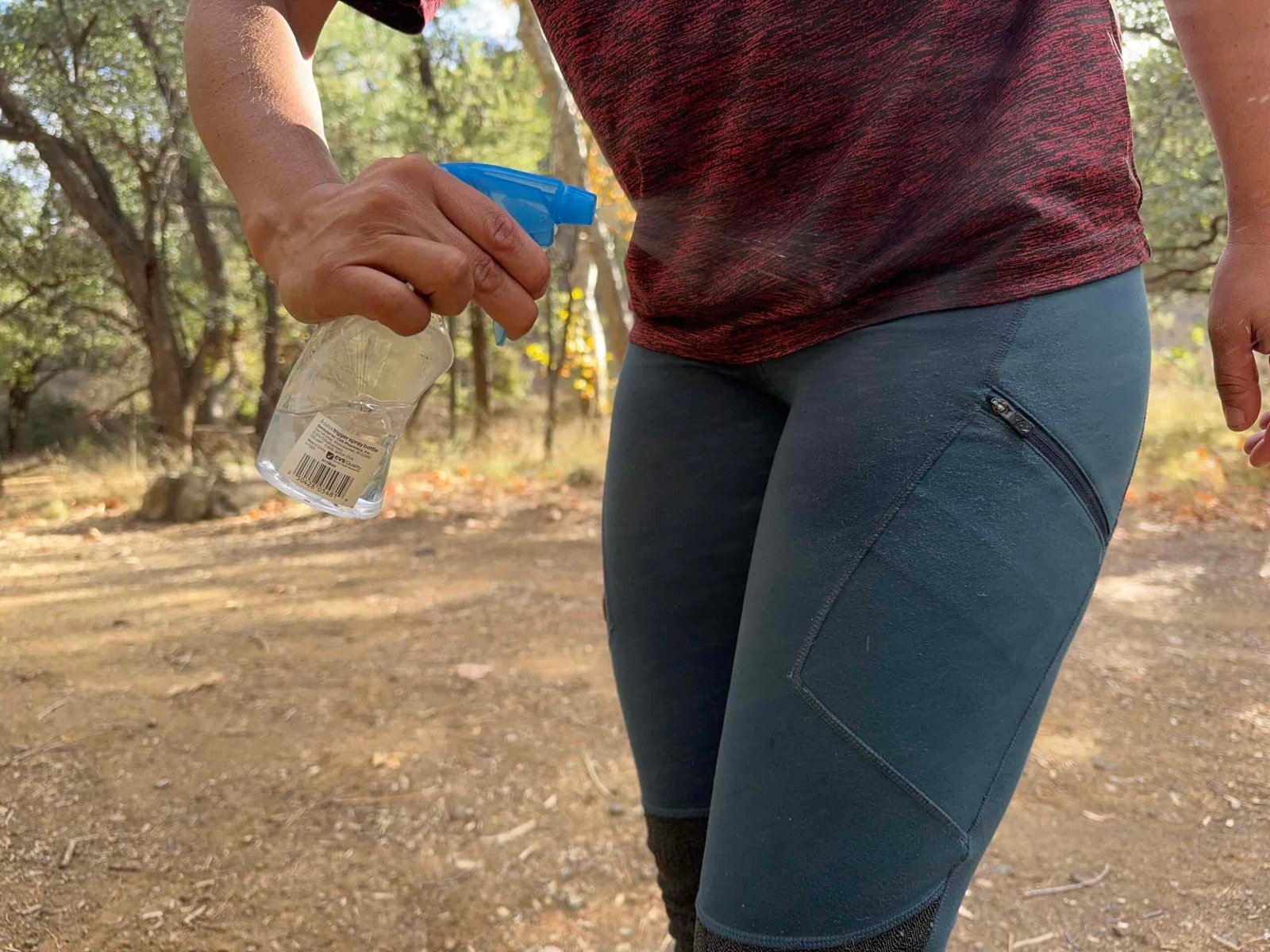 A hand is spraying the Fjallraven Abisko pants with water from a squirt bottle.