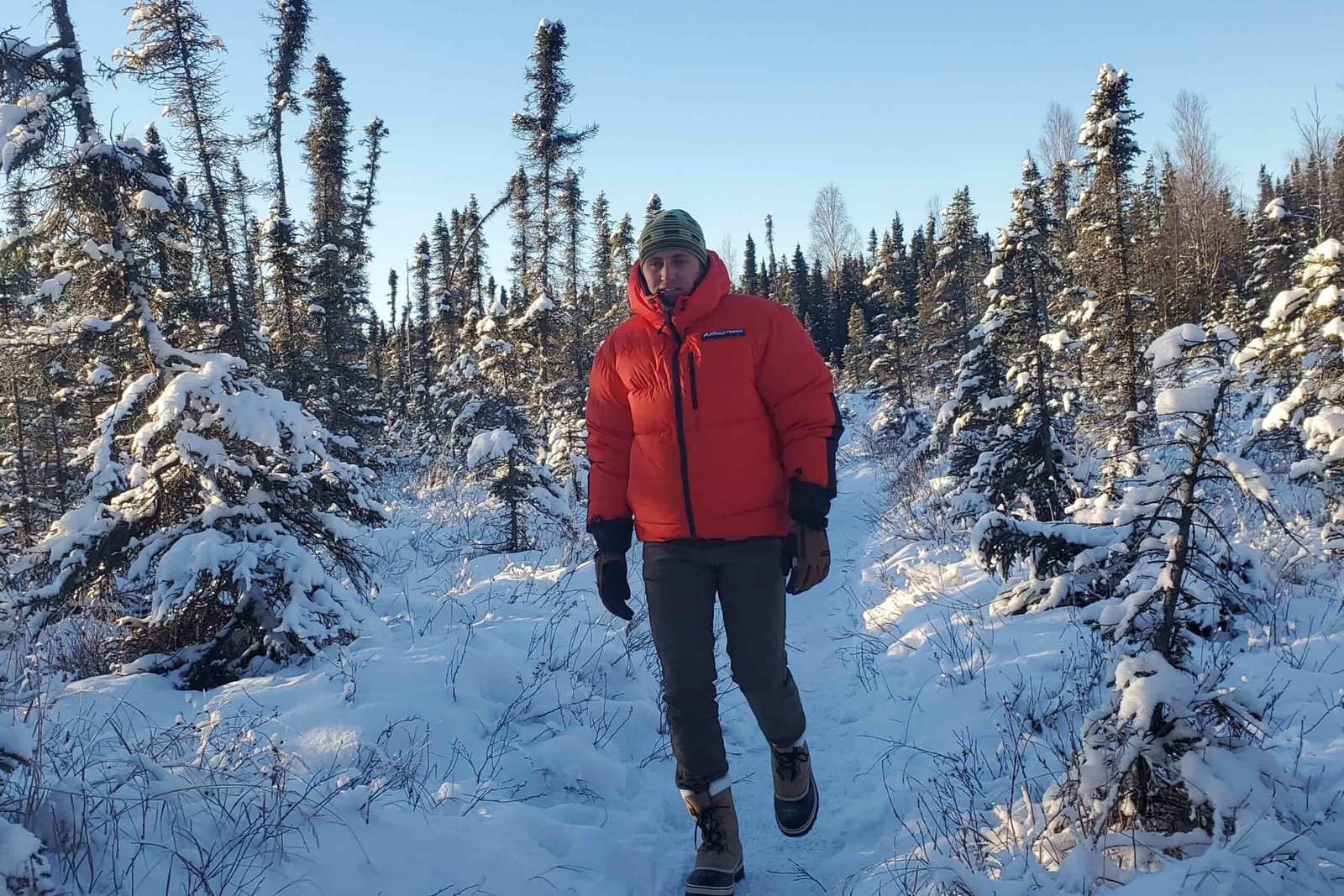 A man walks down a snowy trail.