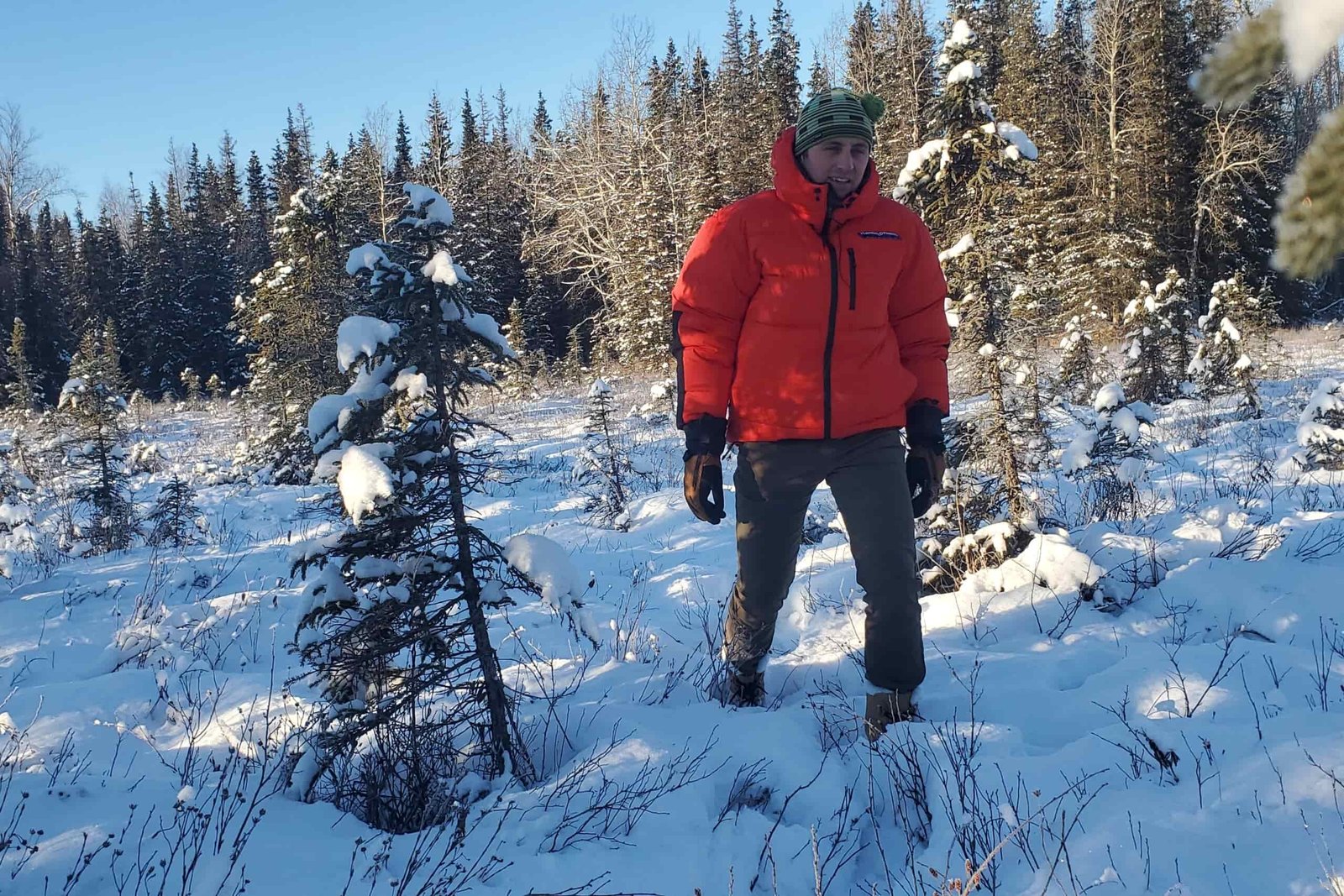 A man walks through a snowy meadow.