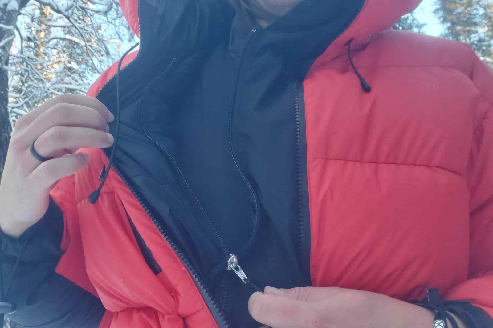 A man unzips the secondary zipper on his down jacket