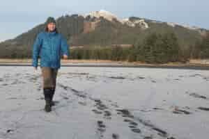A man walks along a snowy beach