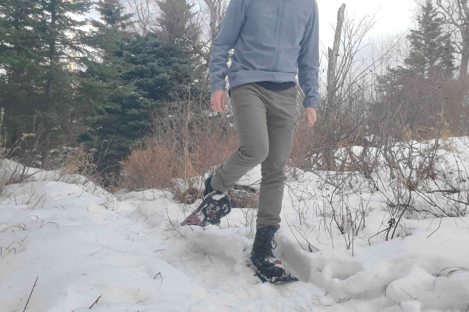 a hiker walking through the snow wearing the tubbs wayfinder snowshoes