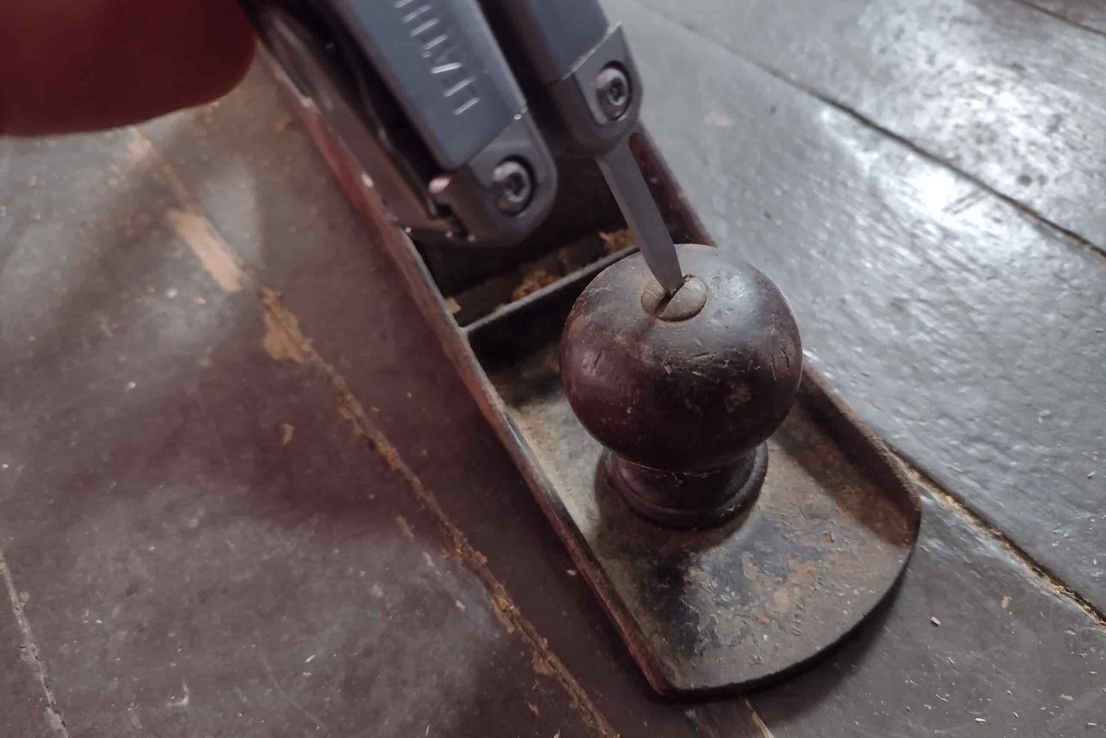 The Leatherman Surge with its standard driver adjusting a screw on an old wood plane.