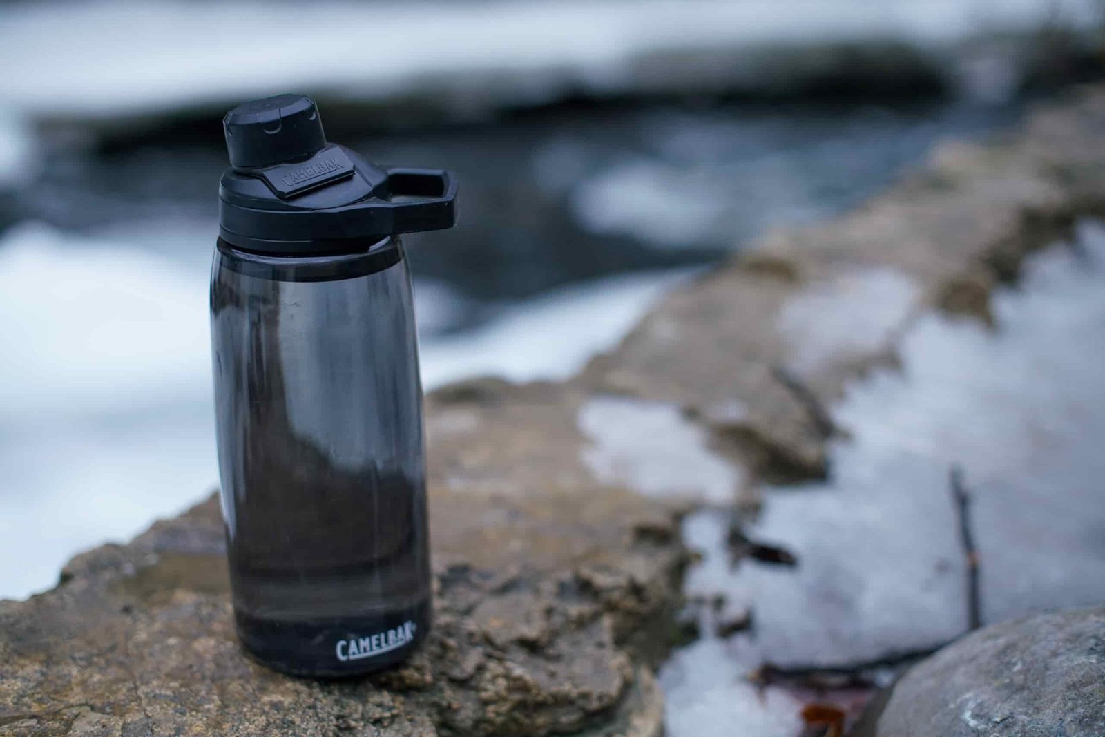 The CamelBak Chute Mag Renew water bottle sitting beside a partially frozen stream.
