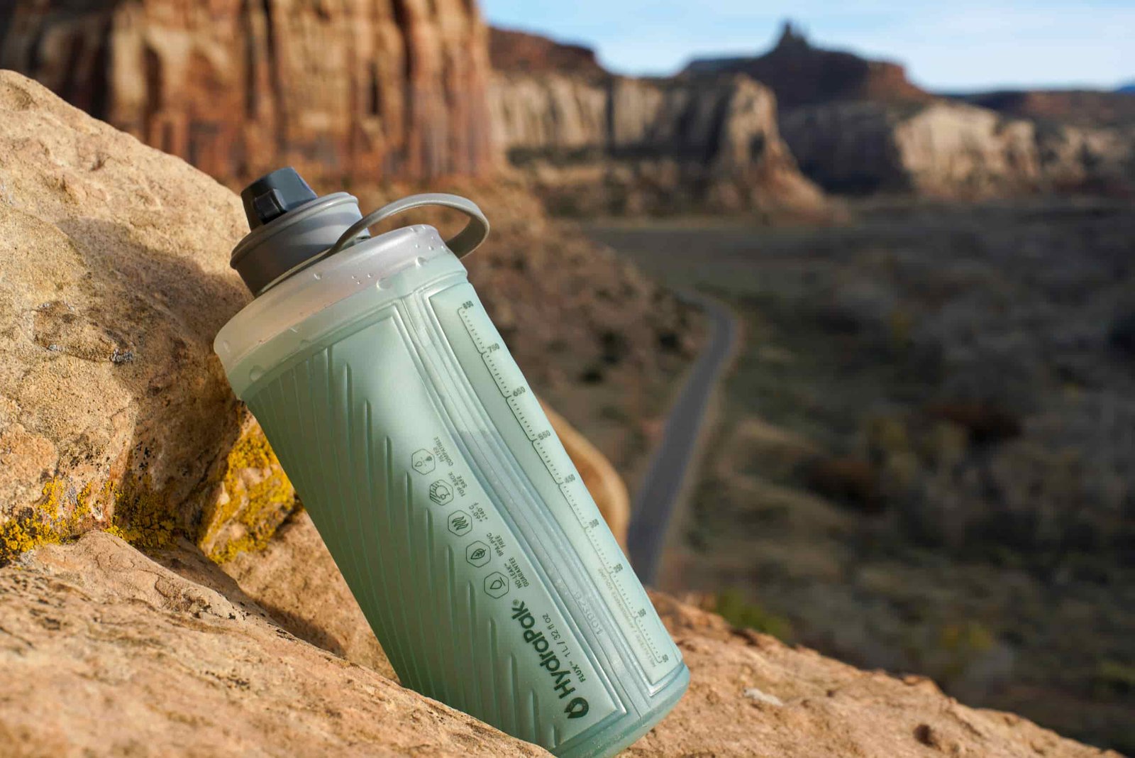 The Hydrapak Flux water bottle rests on a rock with mesas in the background.