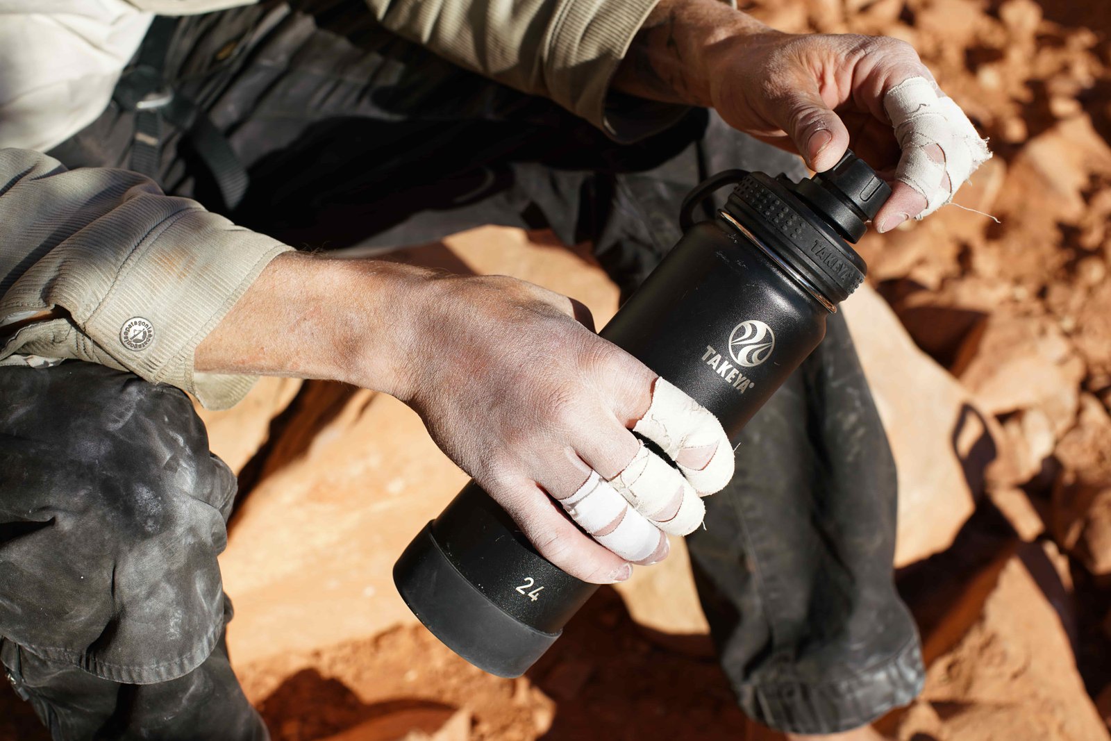 A close up of a person with fingers taped for crack climbing holds the Takeya Actives Insulated water bottle.