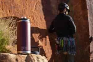 The YETI Rambler sits on a rock with a climber standing in the background.