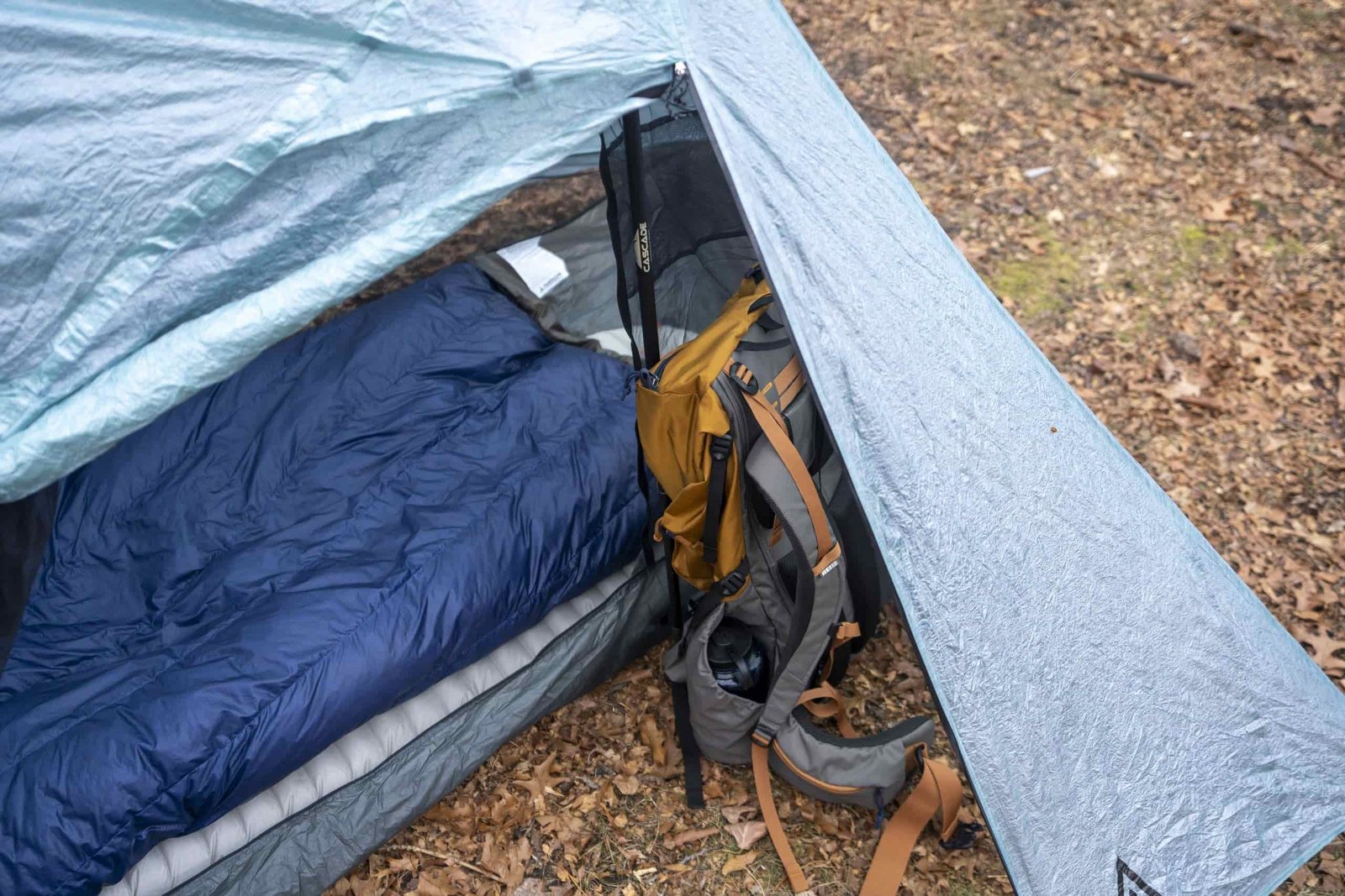 a vestibule of a one person tent holding a backpack