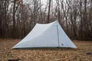 a two person trekking pole tent in a forest clearing