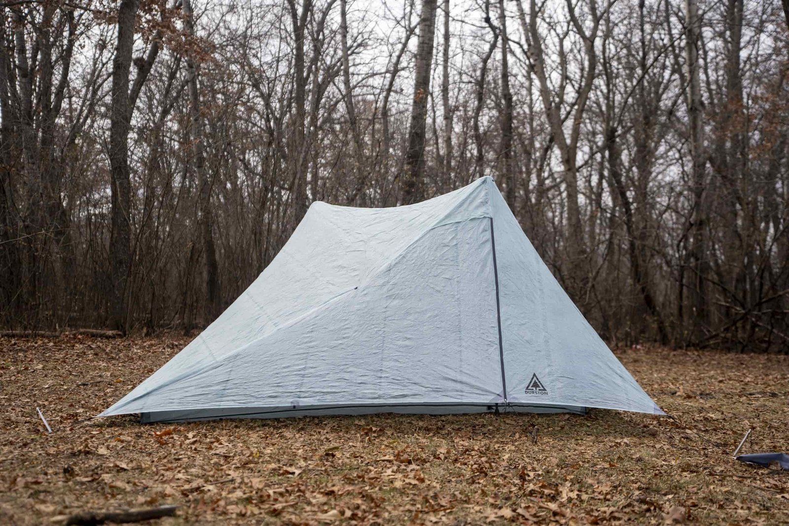 a two person trekking pole tent in a forest clearing