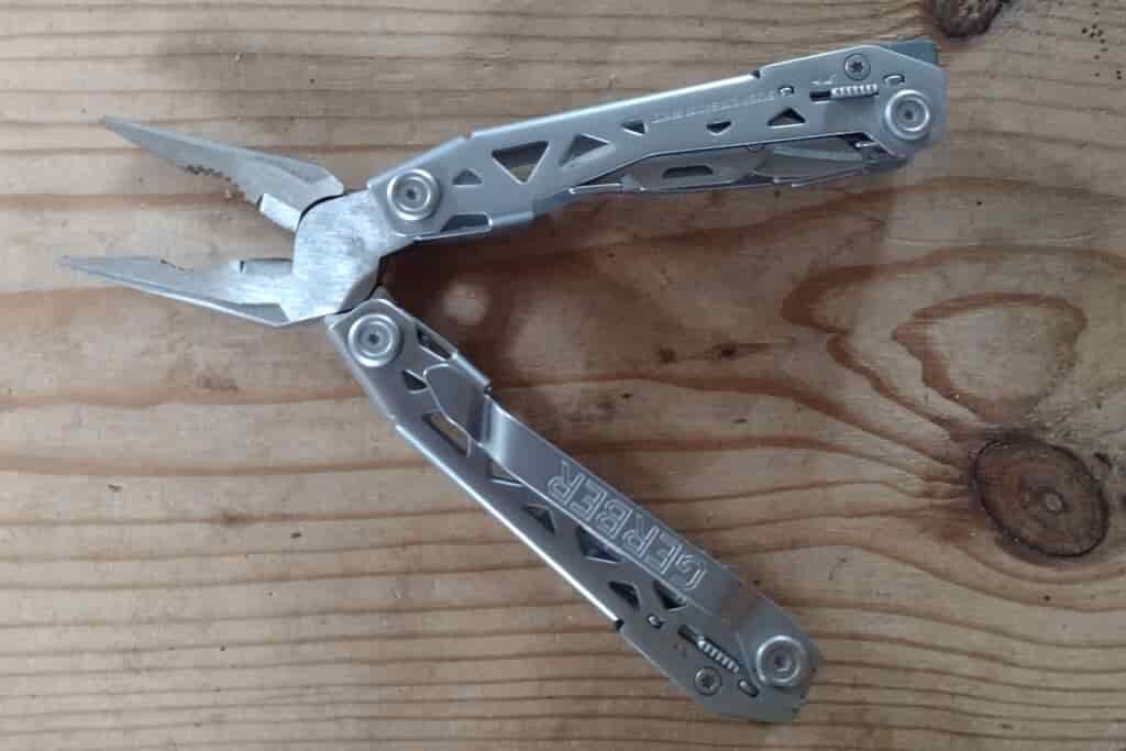 The silver Gerber Suspension NXT with its pliers open, on a board.