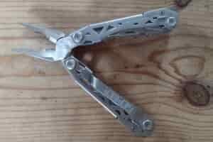 The silver Gerber Suspension NXT with its pliers open, on a board.