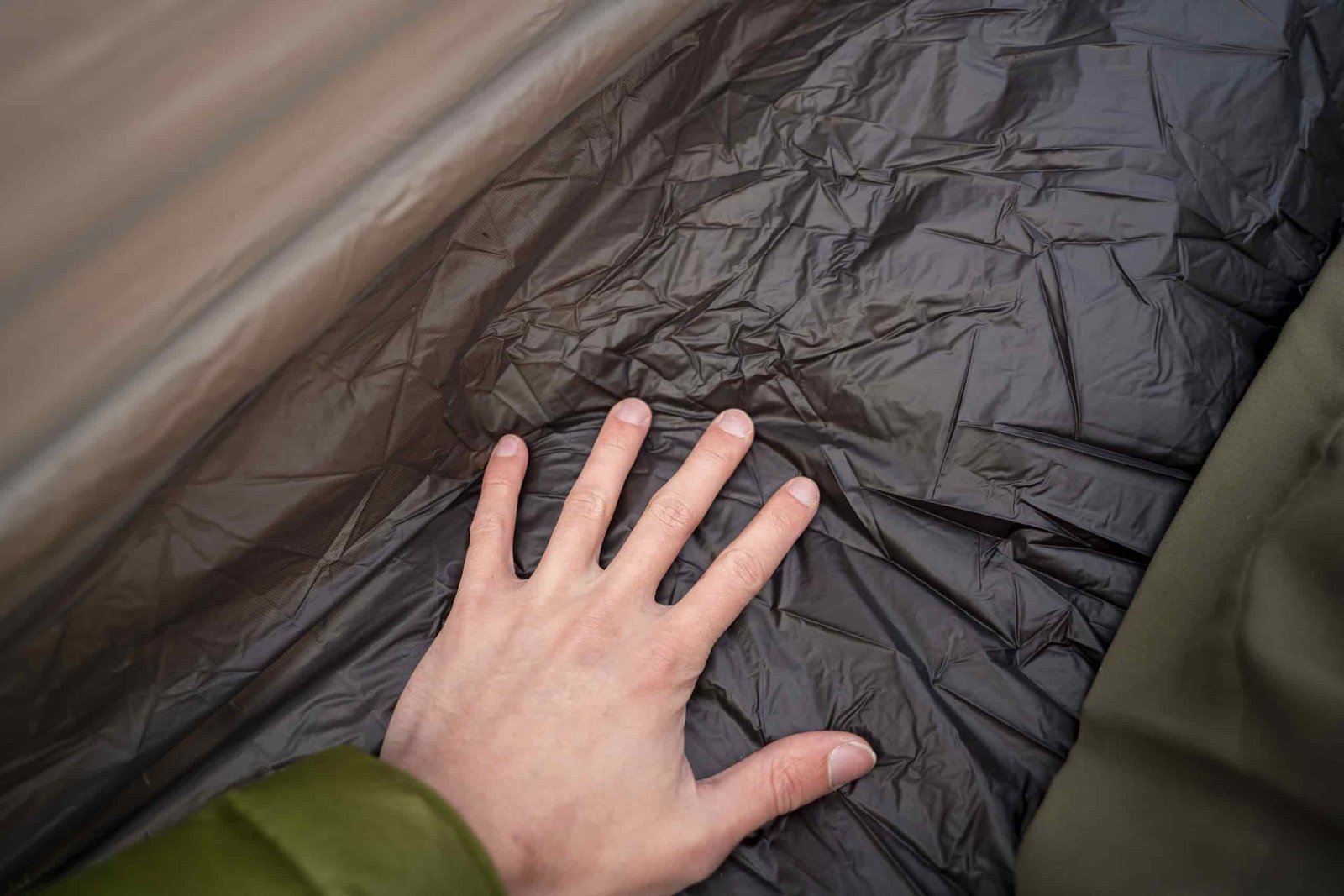 a hand touches a tent floor