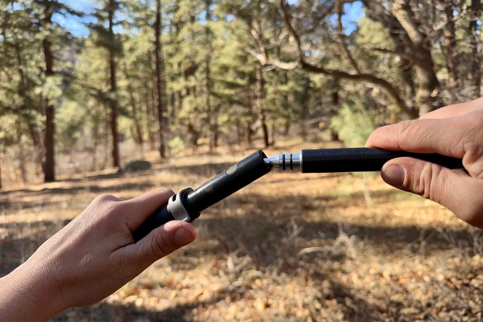 A close up of two hands folding joint on the Durston Iceline trekking poles in a forest.