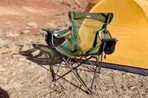 A camping chair in the desert in front of a tent.