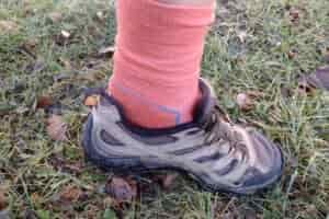 Closeup of someone wearing the light red colored Icebreaker Hike + Light socks in tan hiking shoes.
