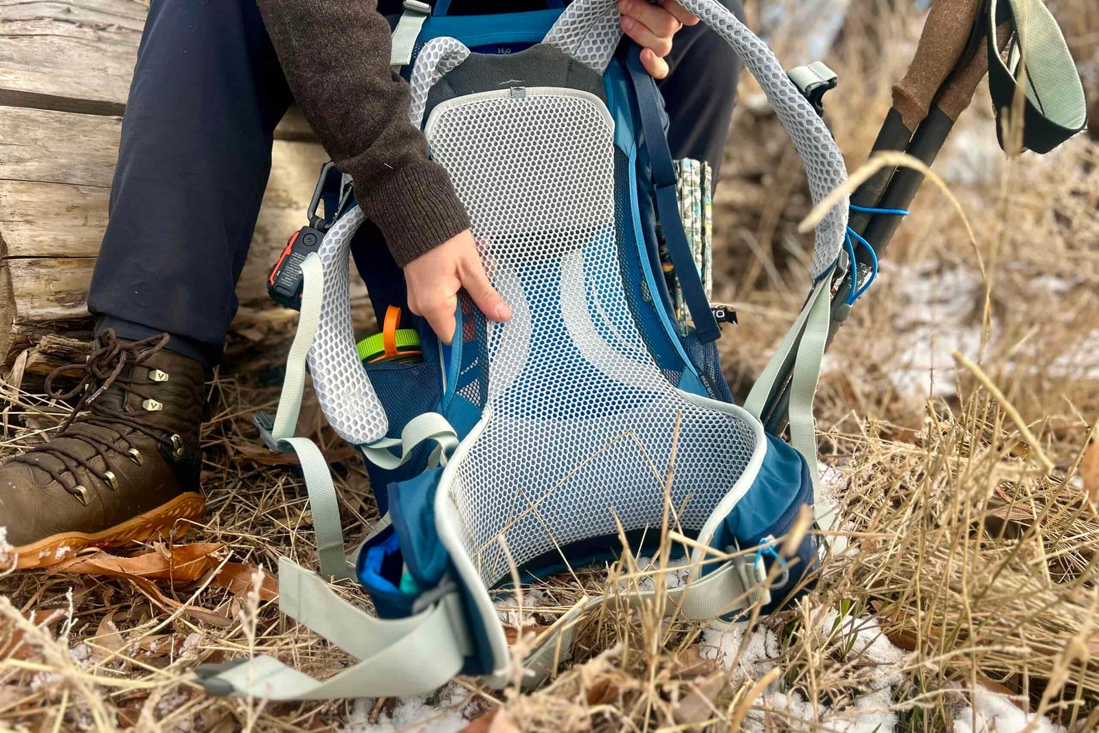Closeup shot of person showing off the mesh lining of a daypack sitting on the ground.