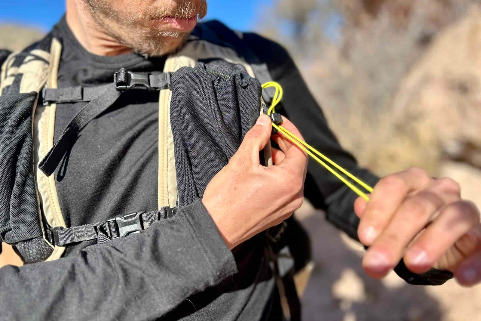 Close up of a man cinching a shoulder strap pocket closed.