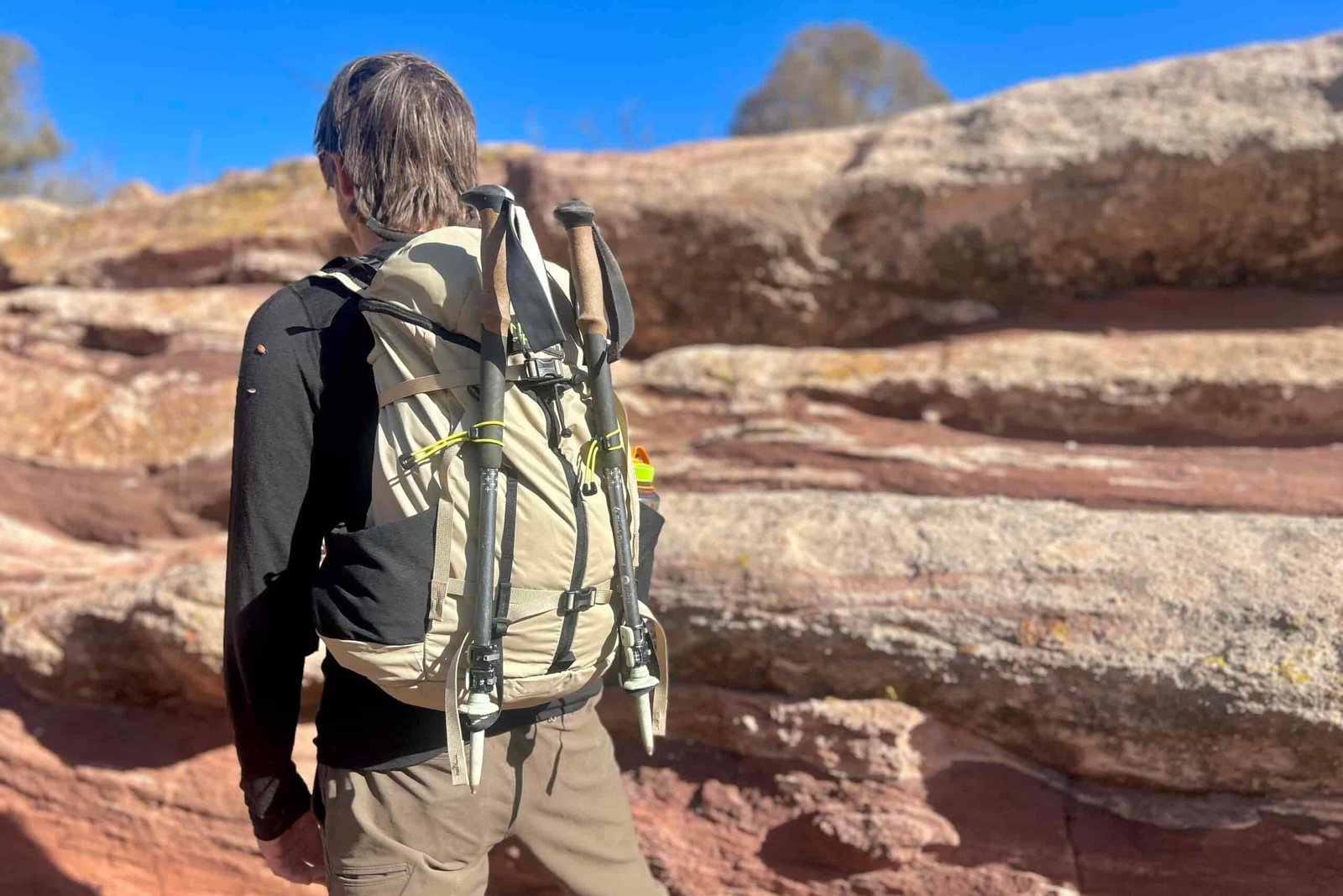 Close up of a man wearing a daypack in a desert setting.