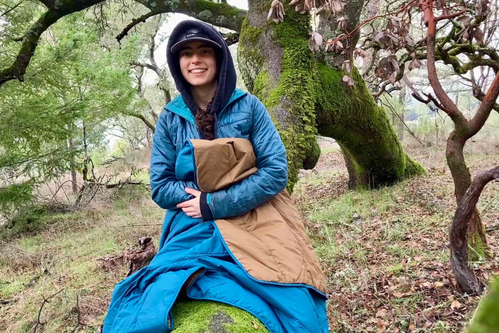 Women sitting on log with the REI camp blanket used as a throw over her legs