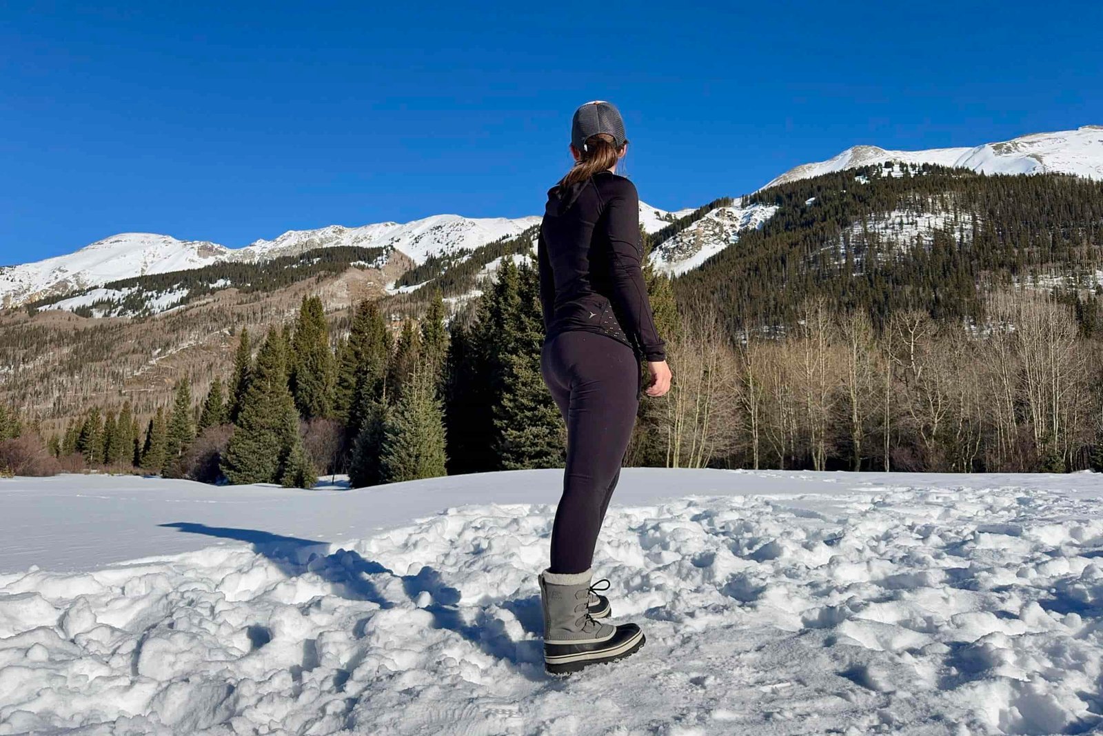 A person taking in a mountain view while wearing the Sorel boots in the snow.