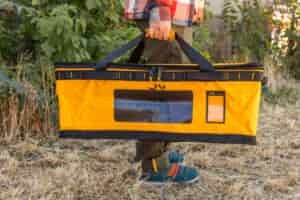 A man carries the Gear Box using the duffel handles on top of the bag.