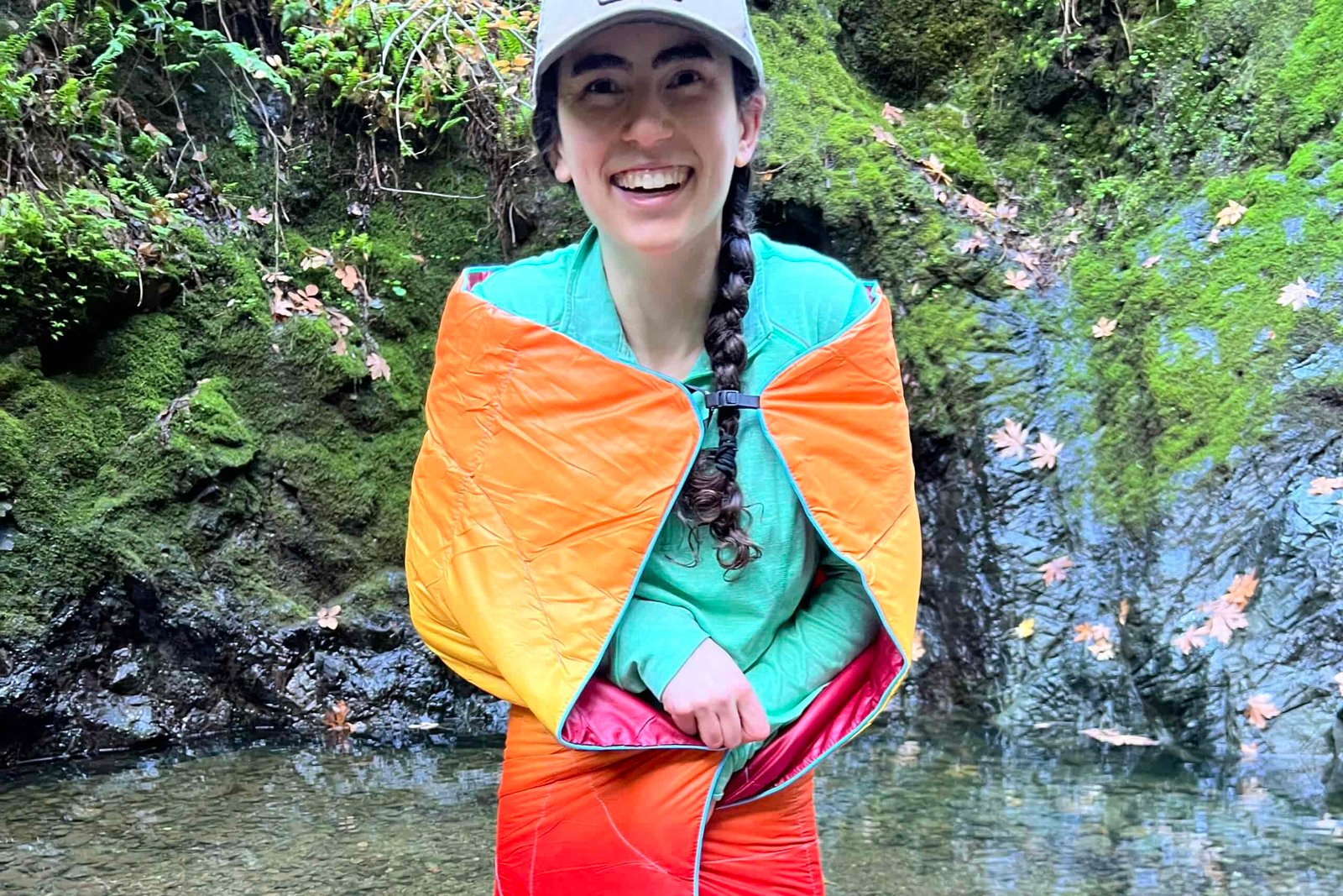 Person wearing the Rumpl NanoLoft Puffy Blanket in cape mode and wrapping the blanket around her body to show its minimal coverage.
