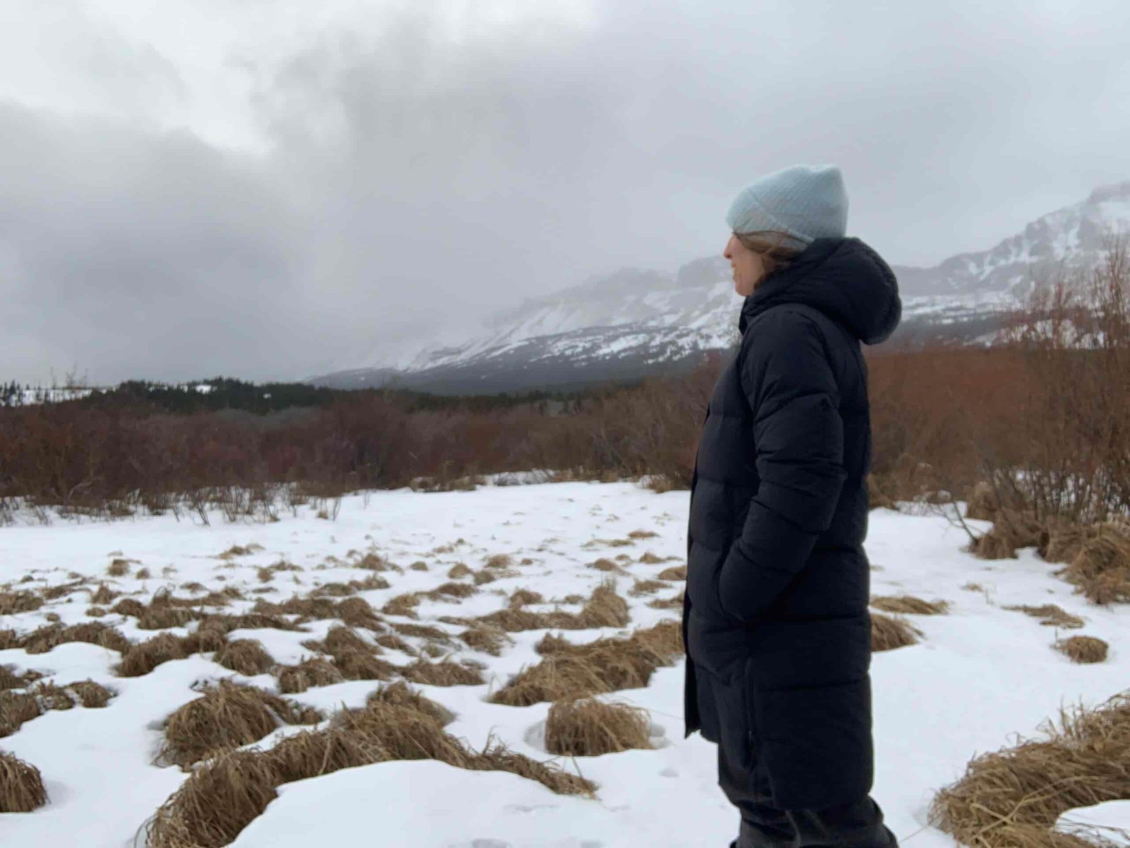 a woman faces into the wind while wearing the warm and wind resistant REI Norseland down parka