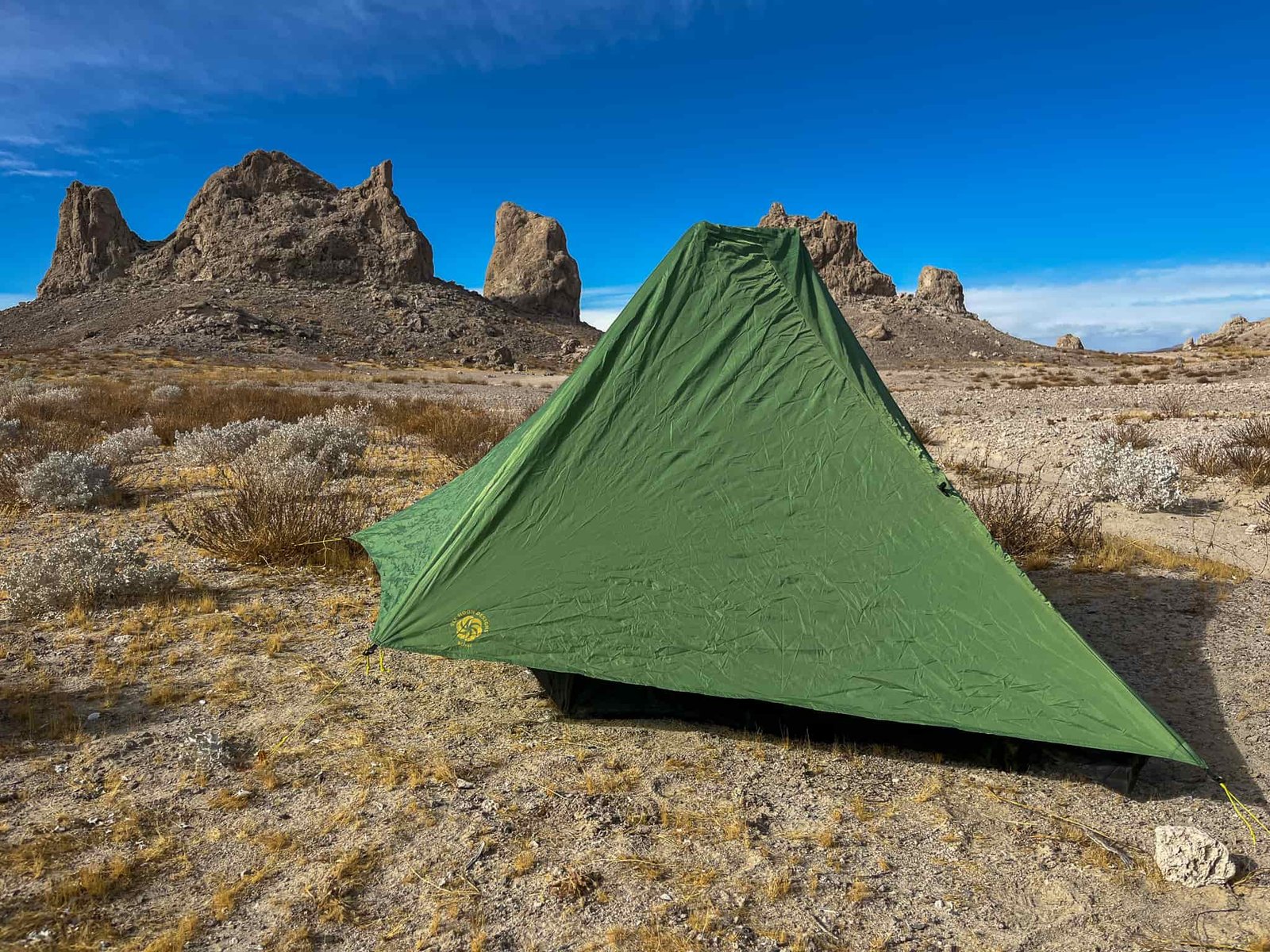 Three quarter view of the Six Moon Designs Skyscape Scout from the head of the tent. The canopy is fully deployed and guyed out and with shrubs and large desert rock pinnacles visible in the background.