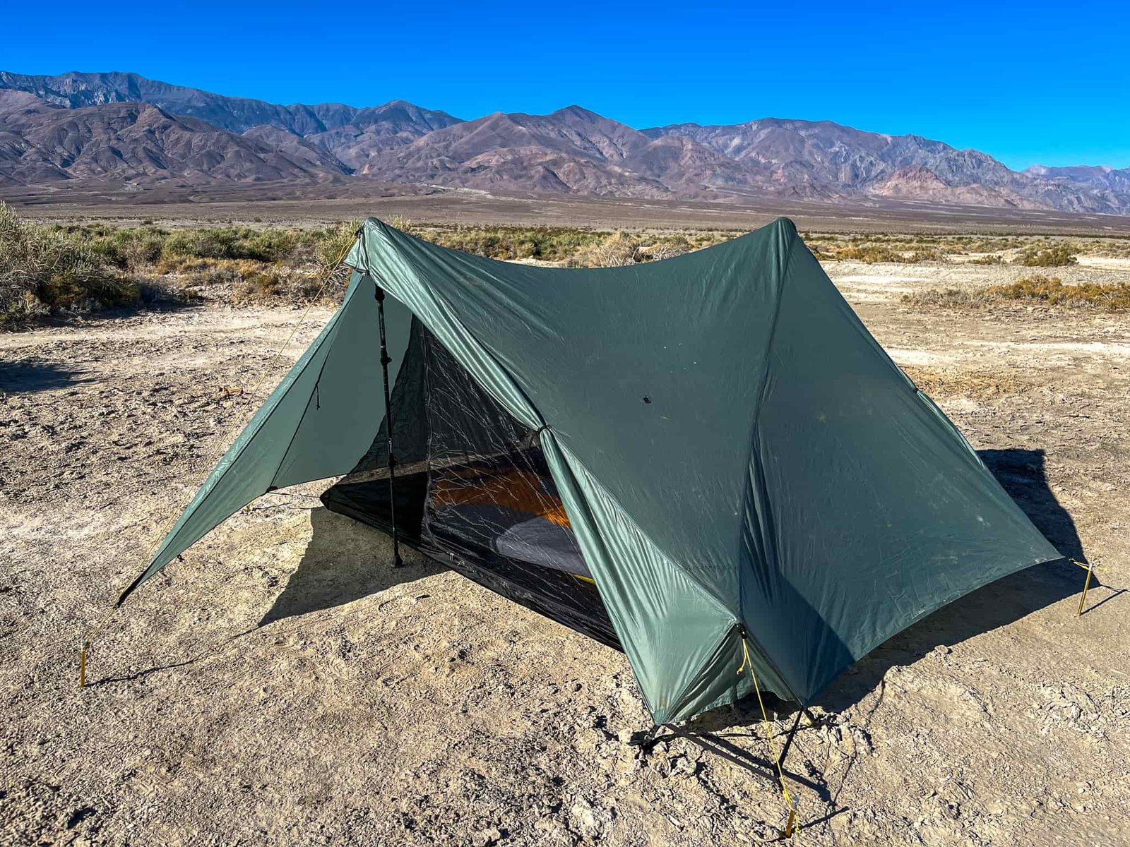 The Tarptent Stratospire 2 pitched with the rainfly and one vestibule door open, revealing the inner mesh and sleeping bag inside. Desert landscape with distant mountains in the background.