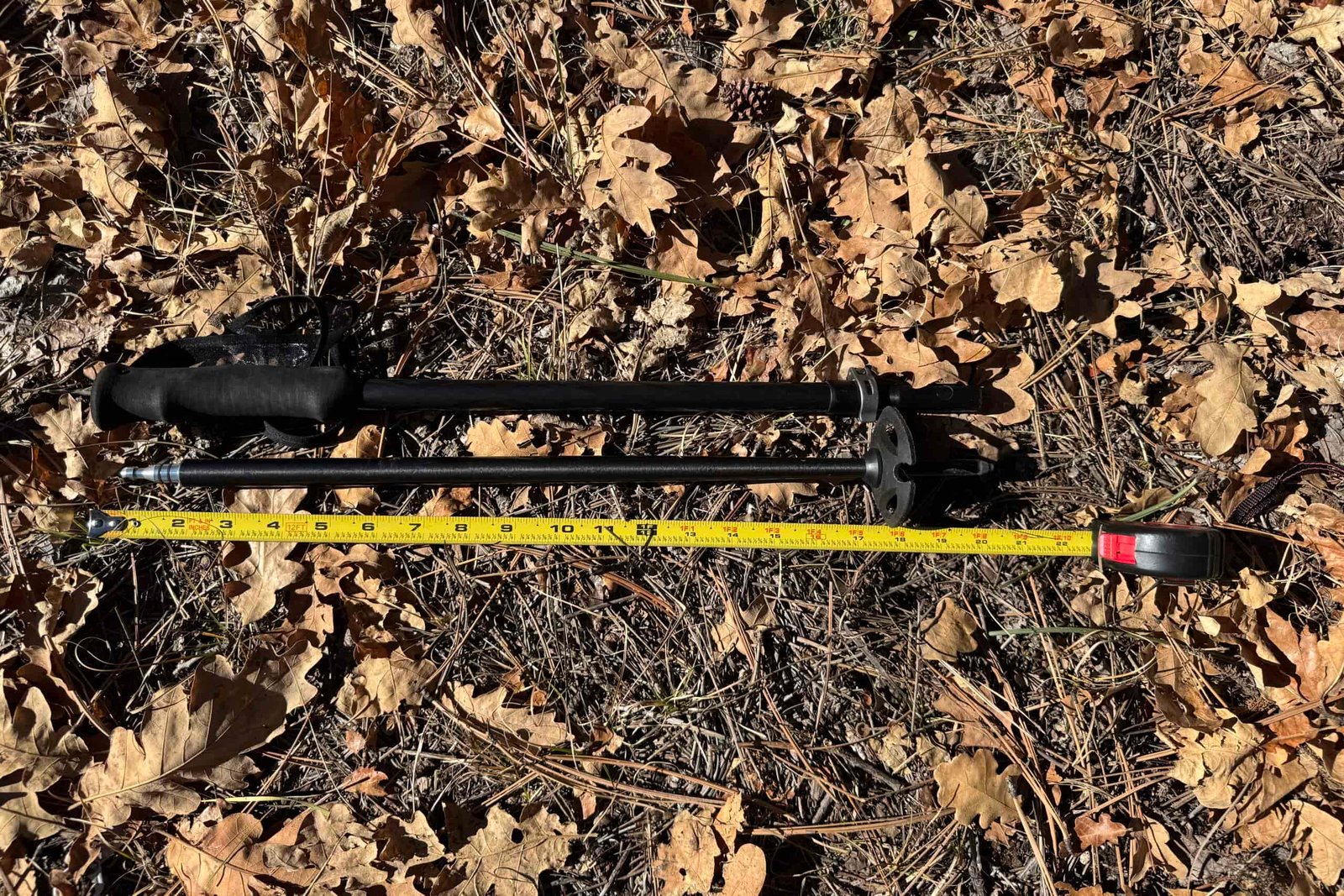 The Durston Iceline pole is laying on the ground in some leaves with a measuring tape next to it.