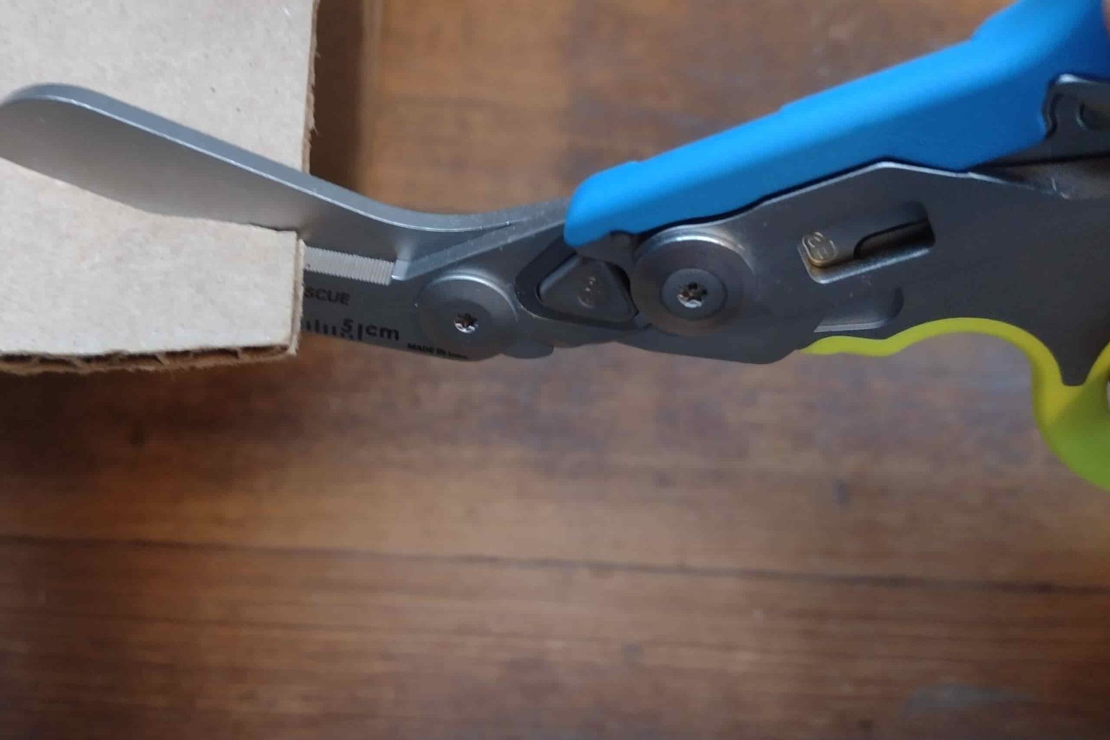 The Leatherman Raptor's blue and yellow handles, and shears cutting cardboard.
